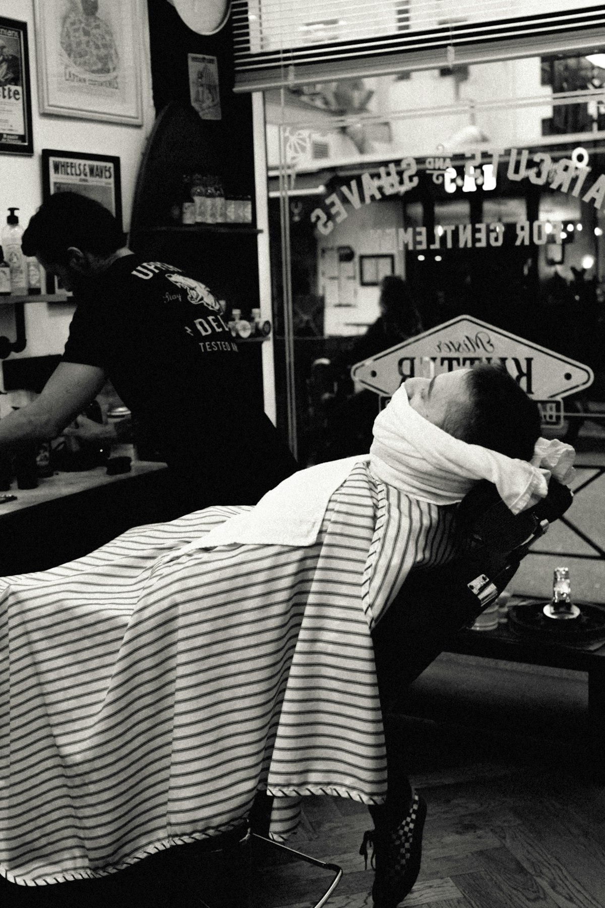 Guest in a grey cape receiving a haircut in a bright shop.