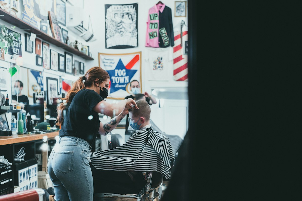 Barber with clippers working along a guest’s hairline.