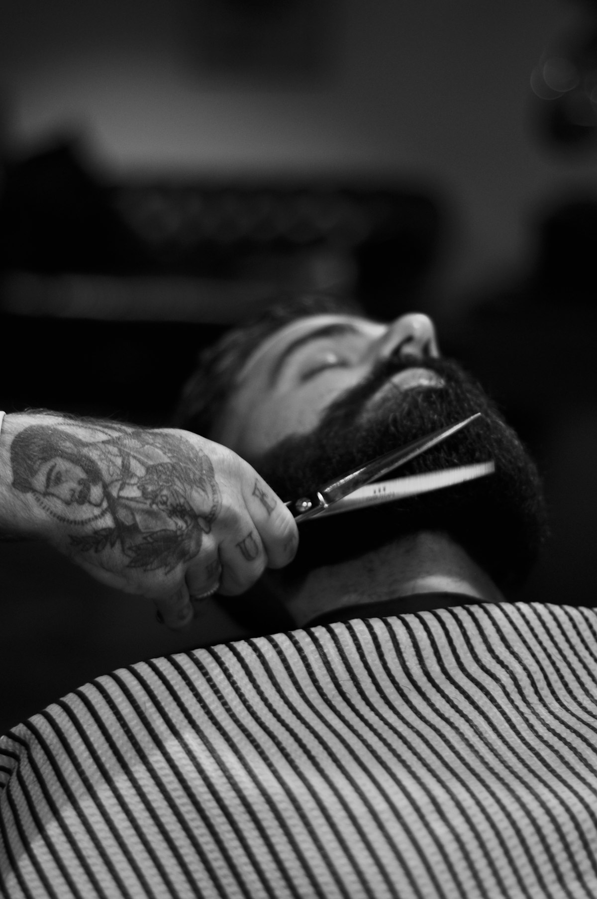 Black-and-white close-up of scissors trimming a beard.