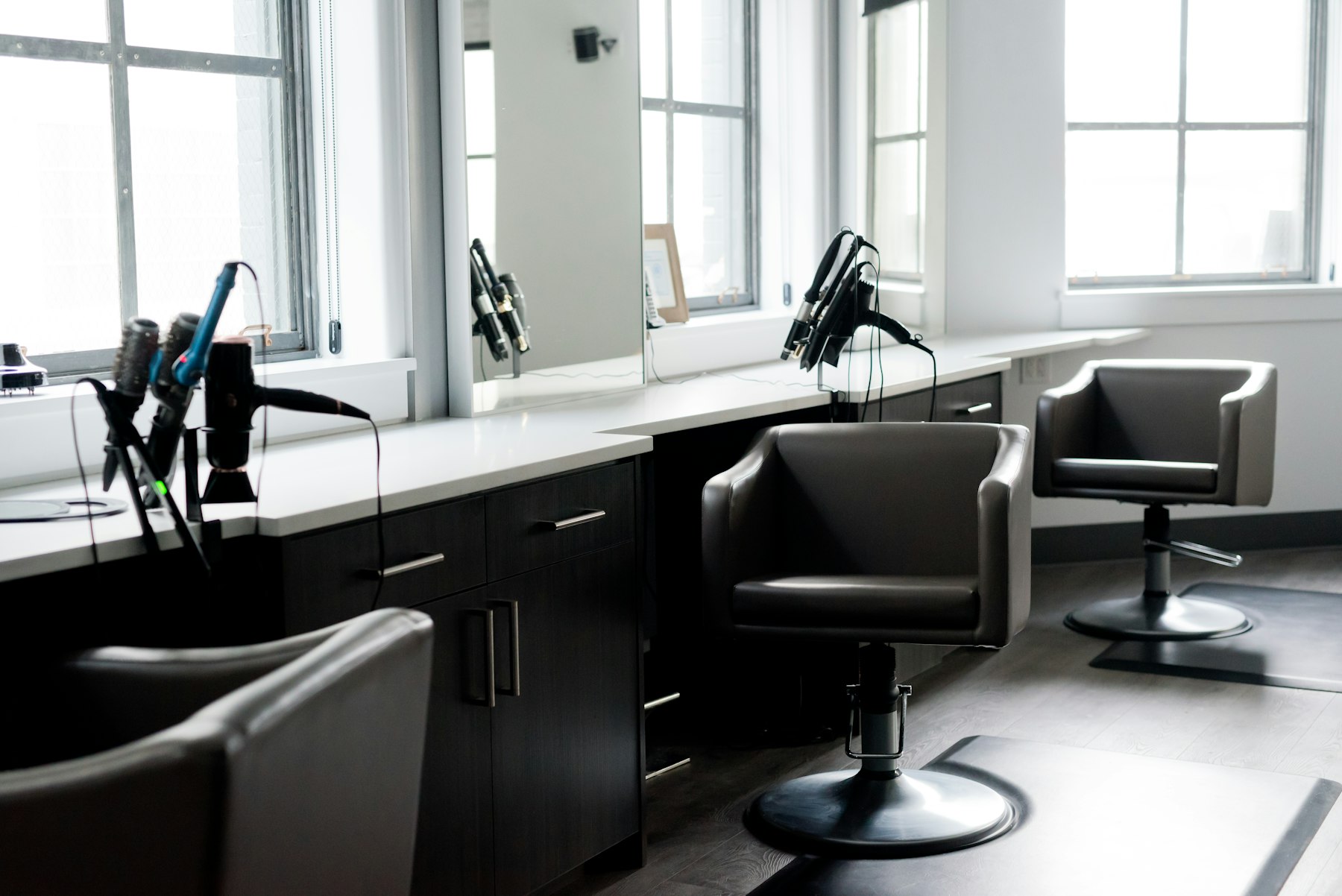 Empty vintage barber chairs in a dim, wood-lined shop before opening.